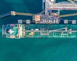 Top-down view of cargo ship being refueled and loaded